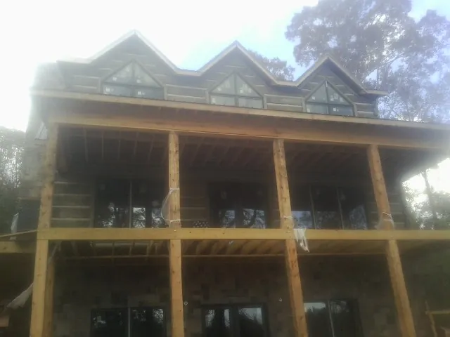 Dormers and porch framing on a large log home under construction — Roof Coating work by our crew in North Haven