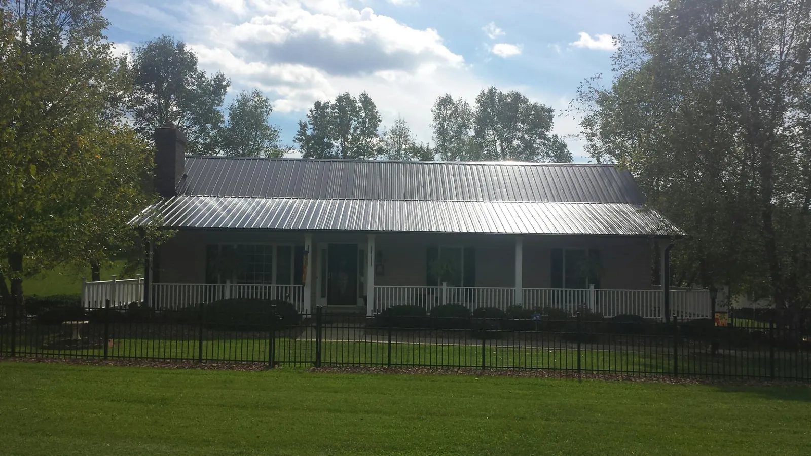 Gray metal roof on a brick ranch with a full width front porch — Gutter Guard Installation work by our crew in North Haven