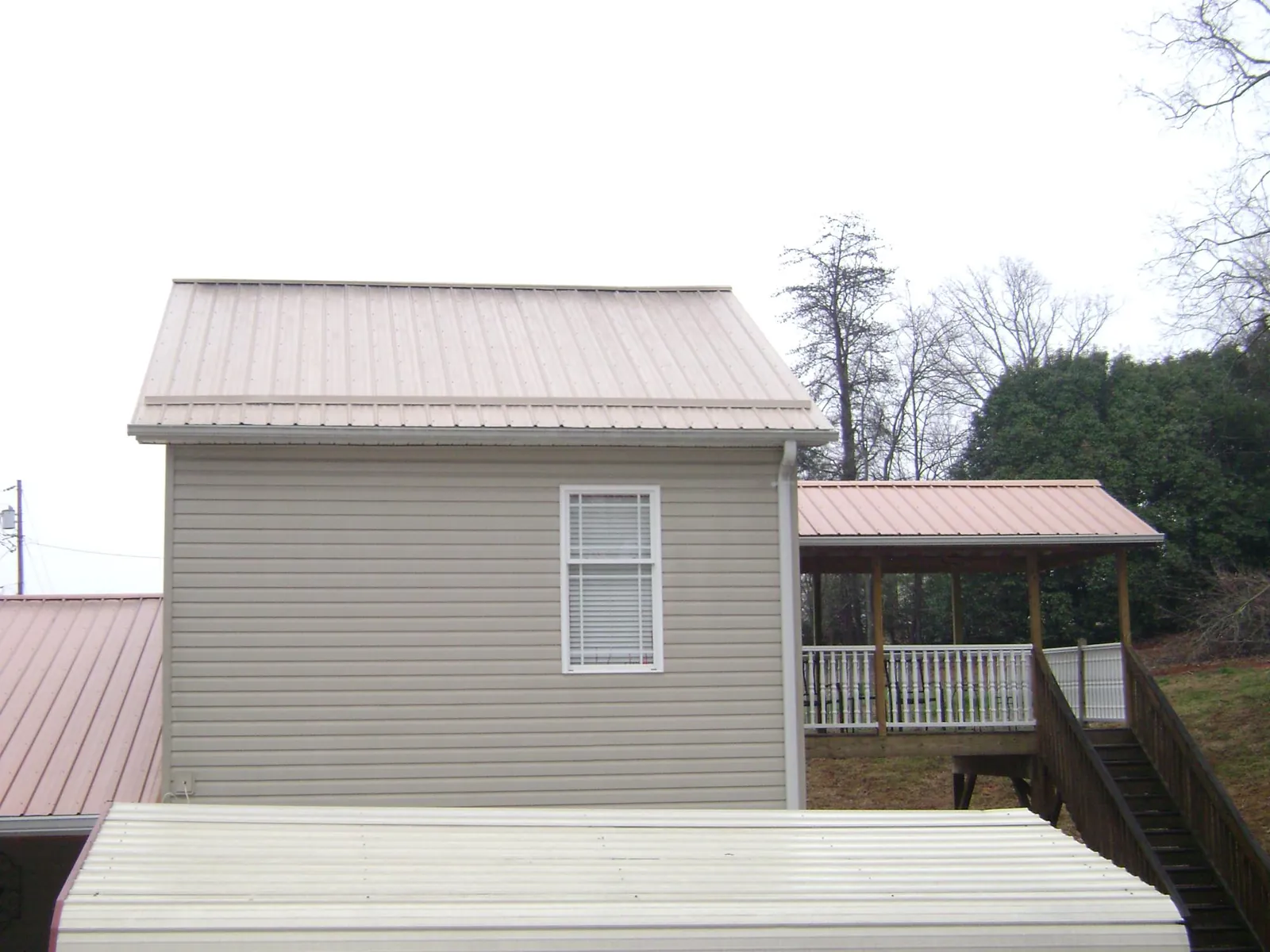 Tan metal roofs on a two story addition and attached porch, from a Roof Replacement job in North Haven