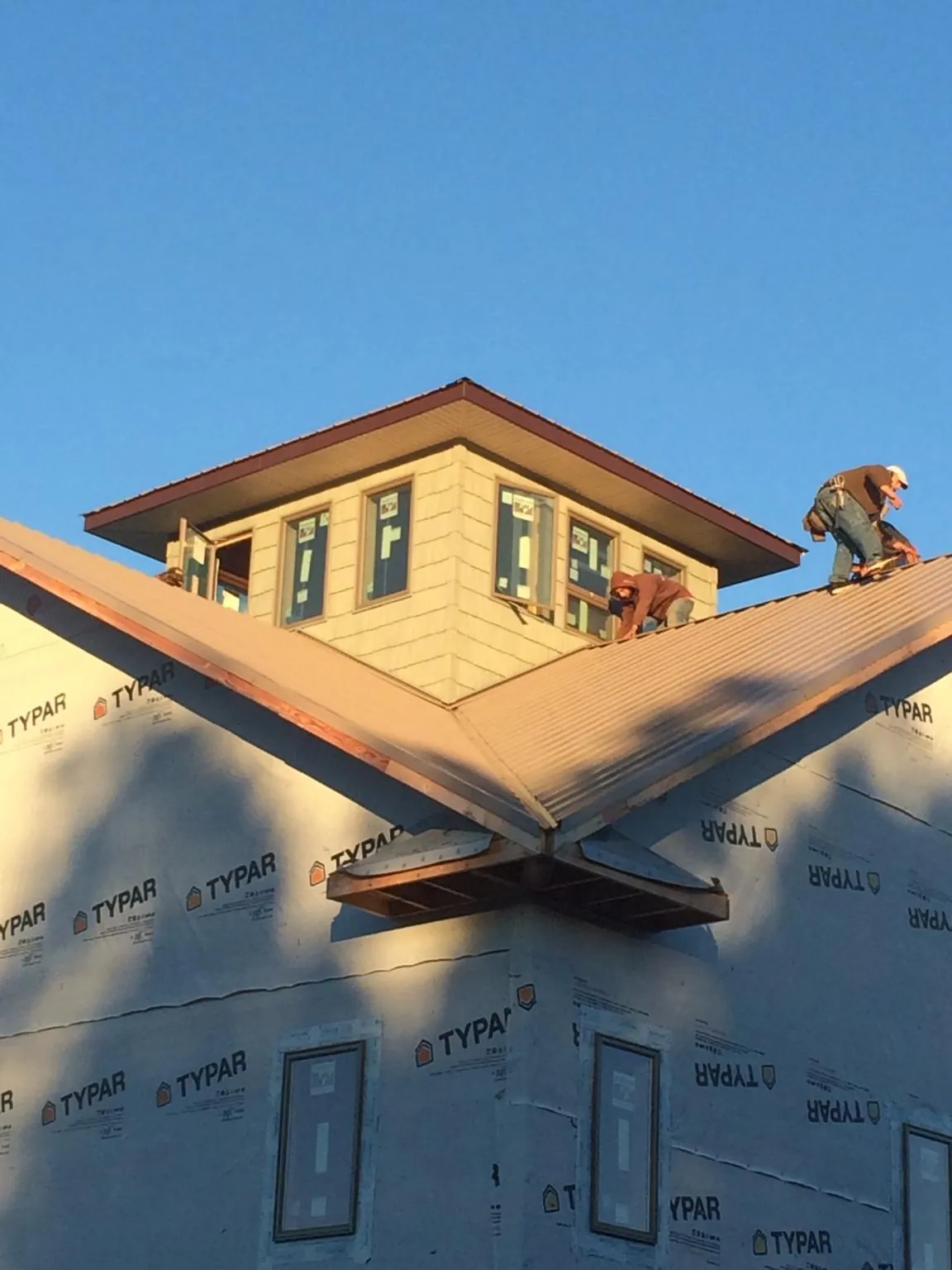 Roofers working around a rooftop cupola on a new metal roof at sunset — Roof Waterproofing in North Haven by Roofing Brothers